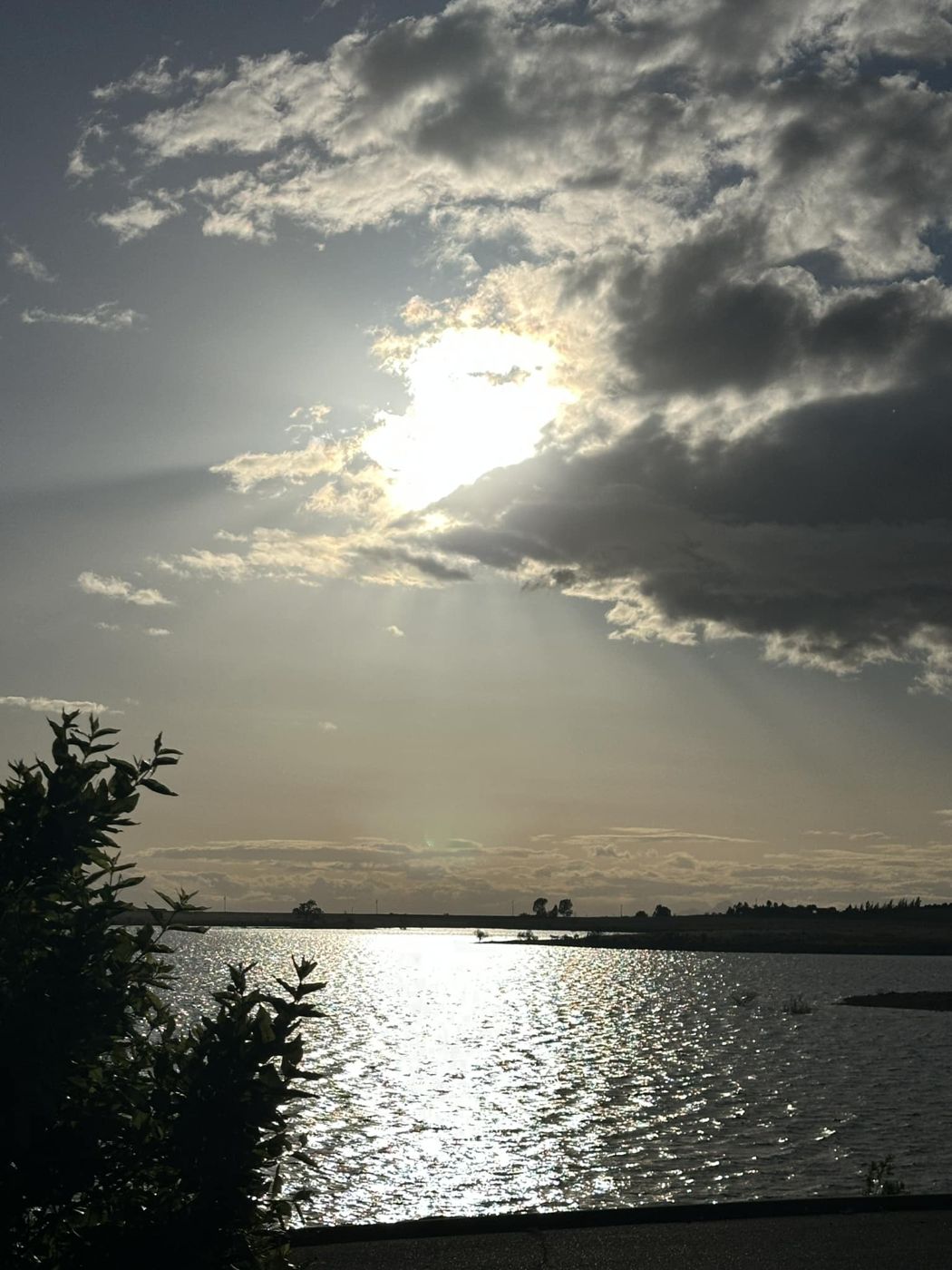 Sun breaking through clouds over Camp Far West Lake at dusk