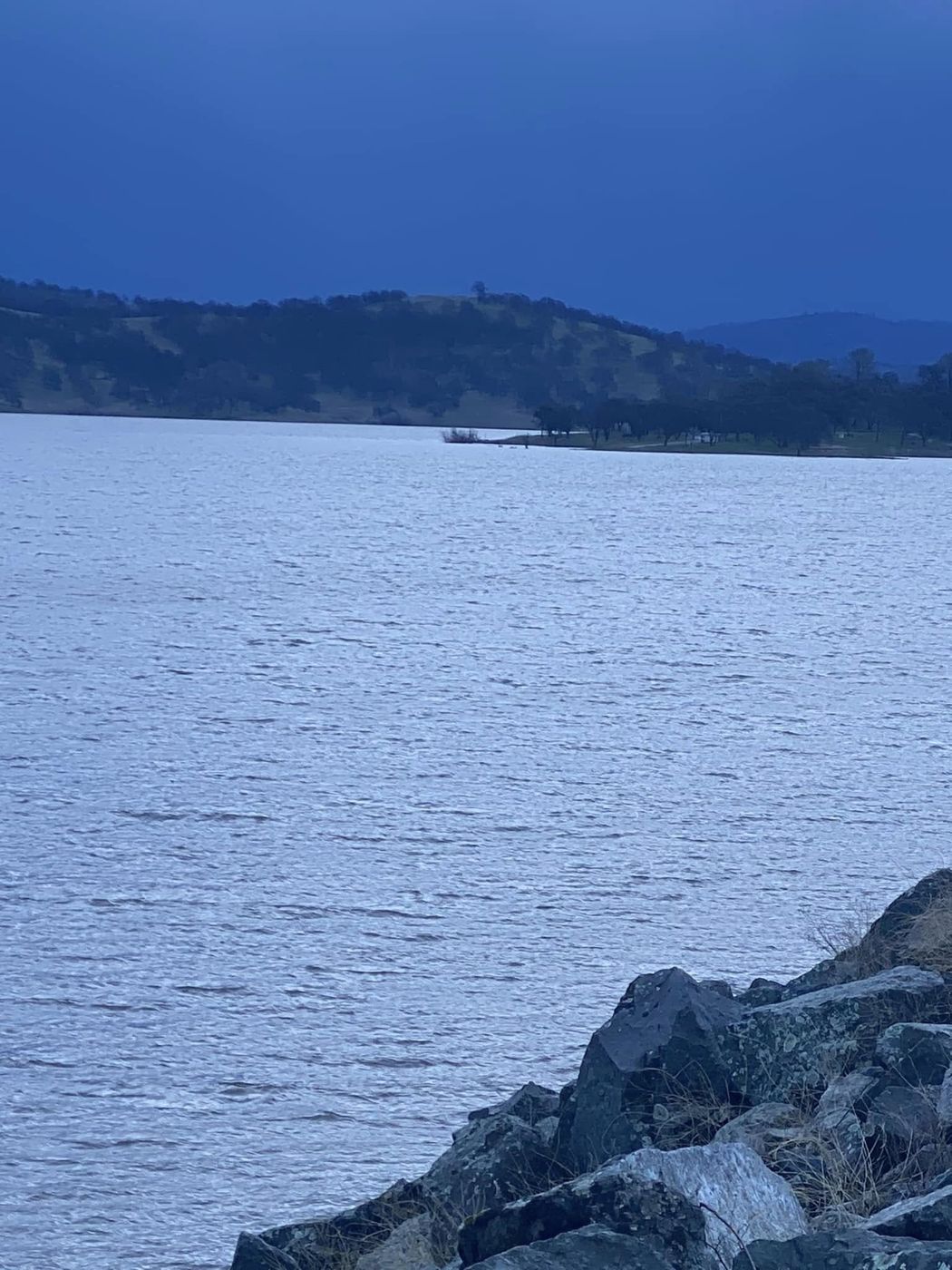Camp Far West Lake at dusk with rocky shoreline and rolling hills